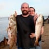 Thomas Mathews of Nederland TX hefts Tapika Clinard's redfish up she caught on finger mullet.
