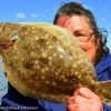 Humble TX anglerette Johnnie Rushing peeking around her flounder she caught on a finger mullet