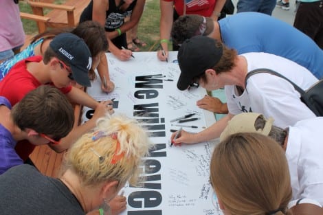 Spectators signing a memorial banner with their personal note for the fallen. At the conclusion of the Memorial Service, the wreath, notes and flowers were transported to Orange, Texas to be displayed on the burial site of a US Marine killed in action, April 5th, 2004 Afghanistan.