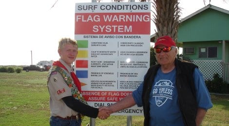 Tyler Ray being congratulated by Mac McDonald in front of a newly installed sign