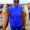 Poochie Walker of League City TX hefts these two nice slot reds caught on finger mullet