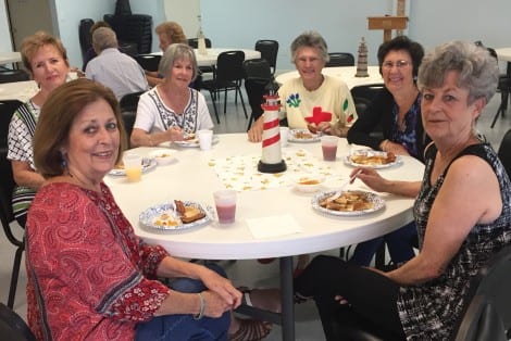 Ladies gather around the table for a fine breakfast.